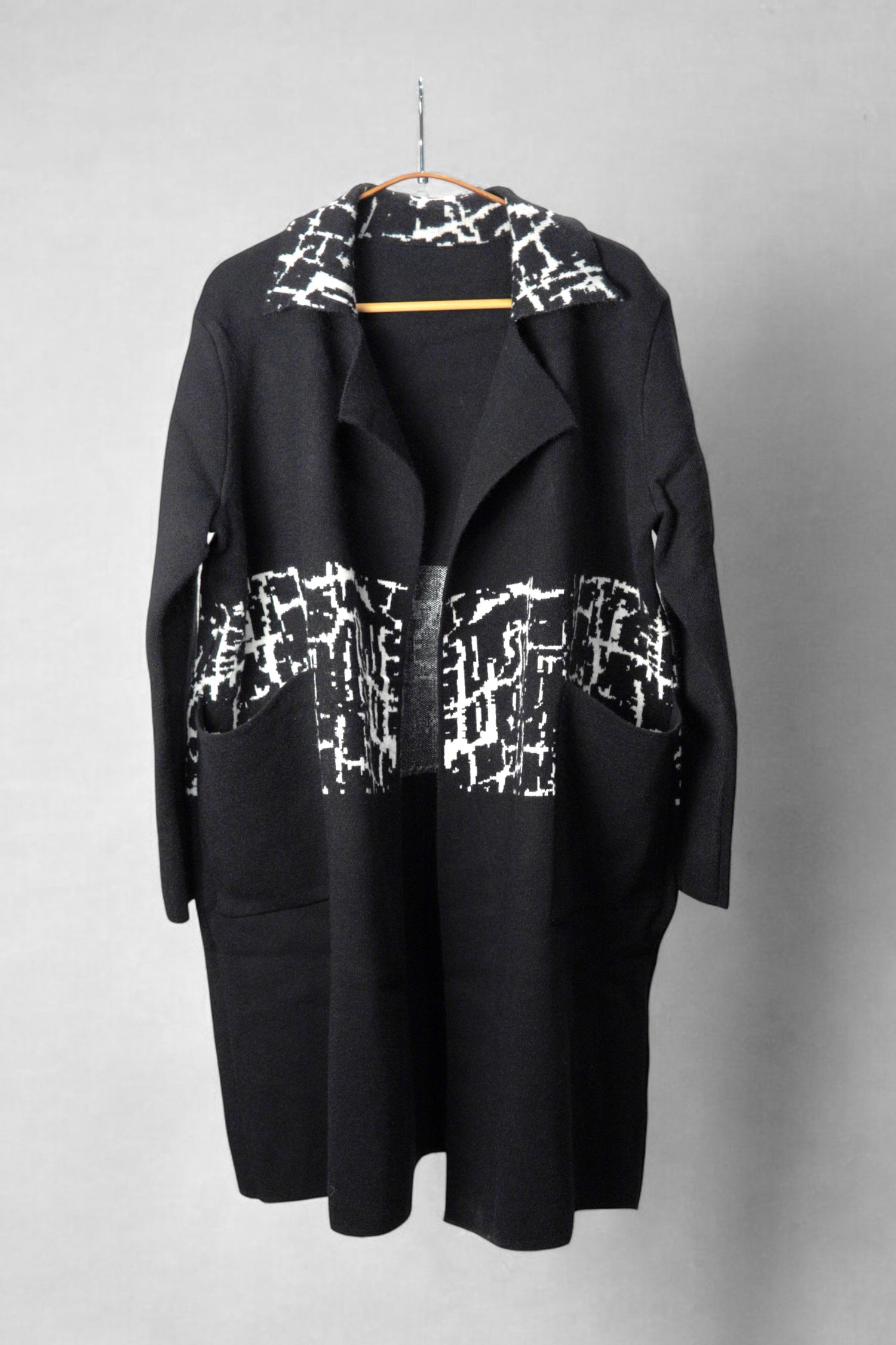 Palton negru cu imprimeu alb, croială lejeră și buzunare aplicate, prezentat pe umeraș.