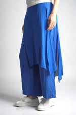 Vedere laterală a pantalonilor asimetrici albastru electric, cu detaliu încrețit în talie.