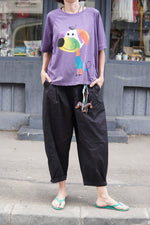 Pantaloni barrel negri, cu breloc decorativ, purtați cu tricou violet imprimat cu cățel