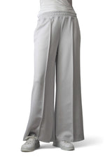 Pantaloni gri largi din material moale, cu talie elastică și cusături verticale, văzuți din față