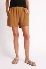 Pantaloni scurți camel, talie elastică cu volănaș discret și buzunare, vedere din față.