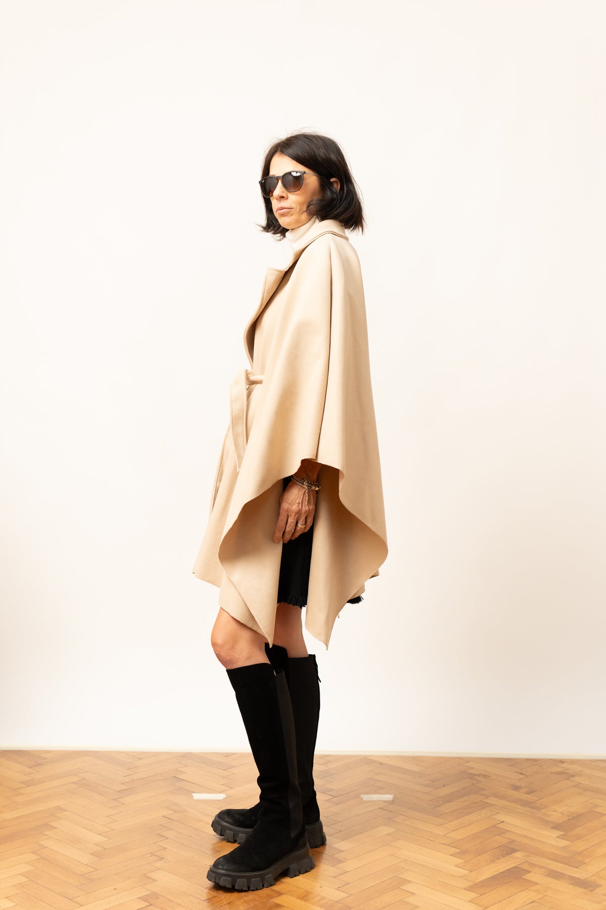 Pelerină bej cu croială lejeră și cordon, prezentare laterală pe model.