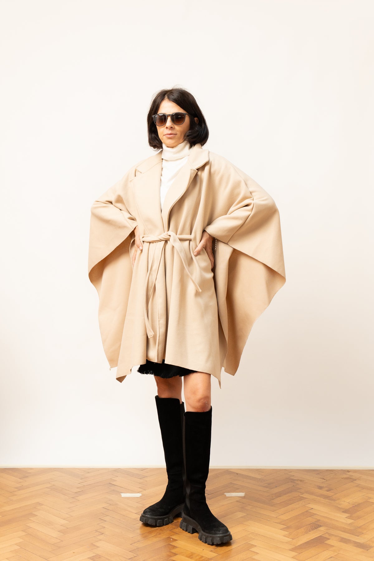 Pelerină tip palton în nuanță bej, cu cordon și croială amplă, privire frontală pe model.