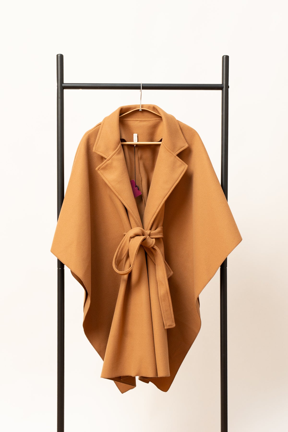 Pelerină camel tip palton, cu cordon și croială largă, prezentată pe umeraș.