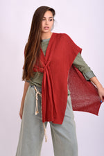 Pelerină tricotată în nuanță roșie, cu croială lejeră și textură fină, purtată peste o bluză verde.