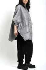 Vedere laterală a ponchoului gri din tricot matlasat, cu cădere amplă și mâneci largi.