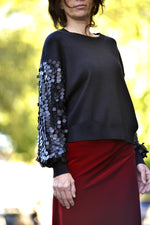 Pulover negru cu paiete pe mâneci, croială lejeră și modernă.