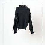 Detaliu cu nasturii metalici contrastanți de pe umărul puloverului tricotat