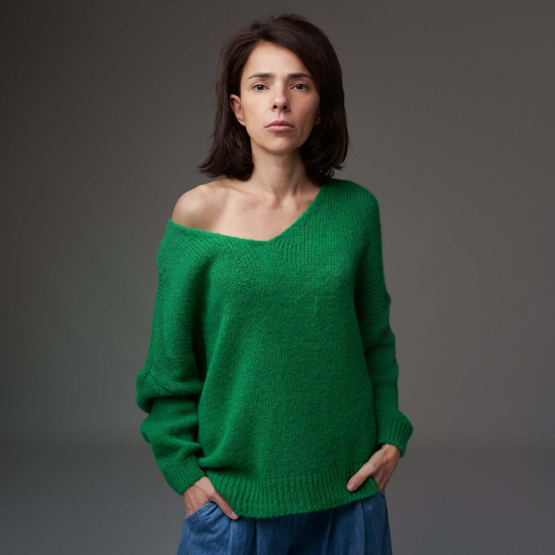 Pulover tricotat verde cu decolteu în V și decupaj lateral, material moale cu fir de lână, model asimetric.