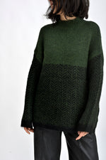 Detaliu textură tricotată în nuanțe de verde, cu model discret și aspect moale.