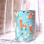 Pușculiță metalică tip conservă, cu imprimeu colorat cu lame și cactuși pe fundal turcoaz.