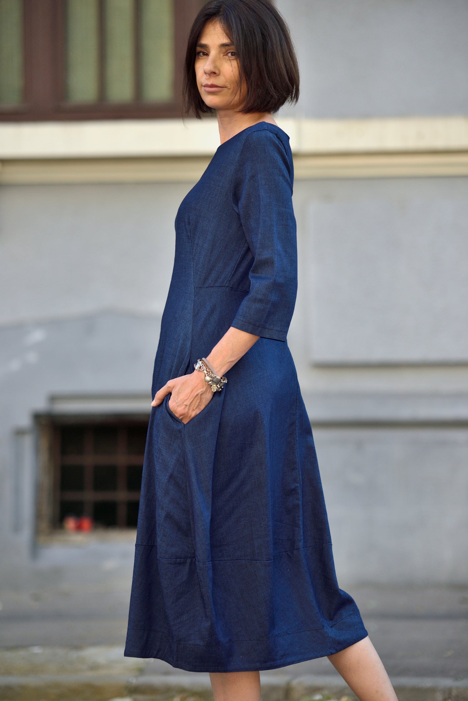 Rochie din denim bleumarin cu mâneci trei sferturi și buzunare, fotografiată din lateral pentru a evidenția linia croielii