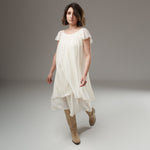 Rochie albă fluidă cu umeri căzuți și volan dublu, în mers, vedere frontală