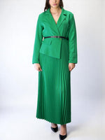 Rochie lungă verde elegantă, cu sacou cambrat și fustă plisată, purtată cu pantofi stiletto negri.