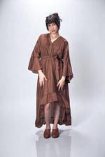 Rochie lungă satinatã maro cu mâneci largi și croi lejer, fotografiată din față.