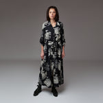 Model purtând o rochie lungă tip cămașă din viscoză, cu imprimeu alb-negru inspirat de natură, croi lejer și cordon în talie, ideală pentru un look casual elegant.