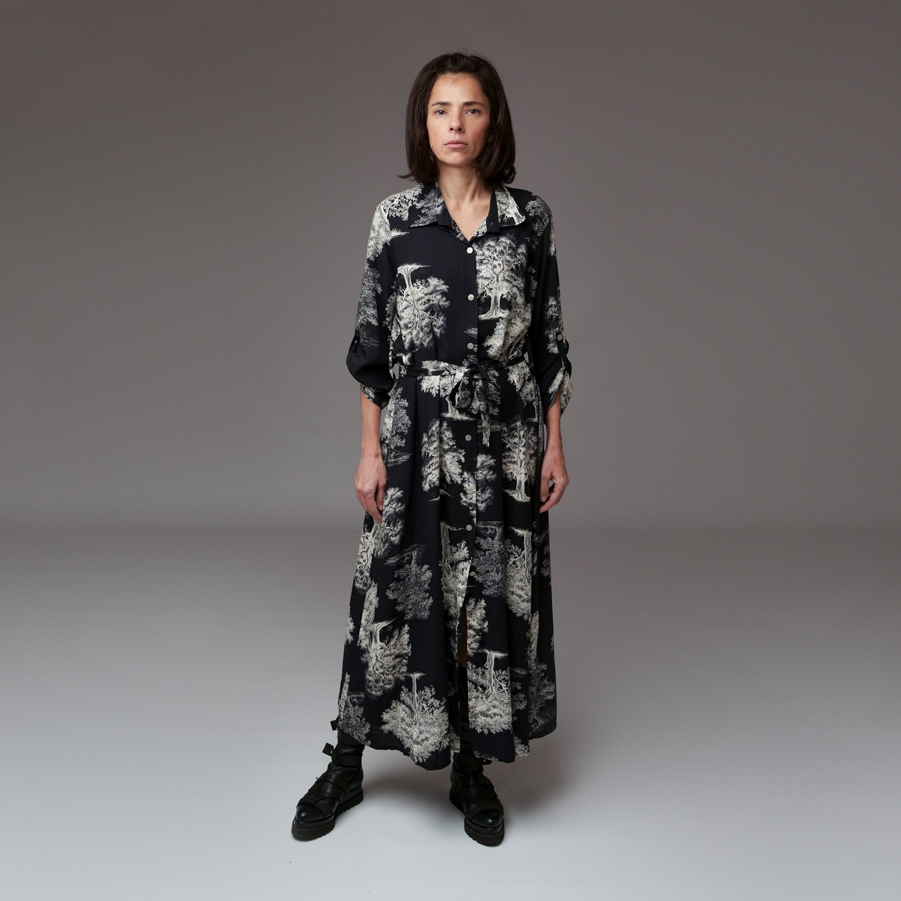Model purtând o rochie lungă tip cămașă din viscoză, cu imprimeu alb-negru inspirat de natură, croi lejer și cordon în talie, ideală pentru un look casual elegant.
