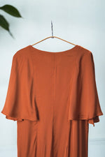 Detaliu al rochiei midi cărămizii cu mâneci fluture, surprinzând finețea materialului și lejeritatea croielii.