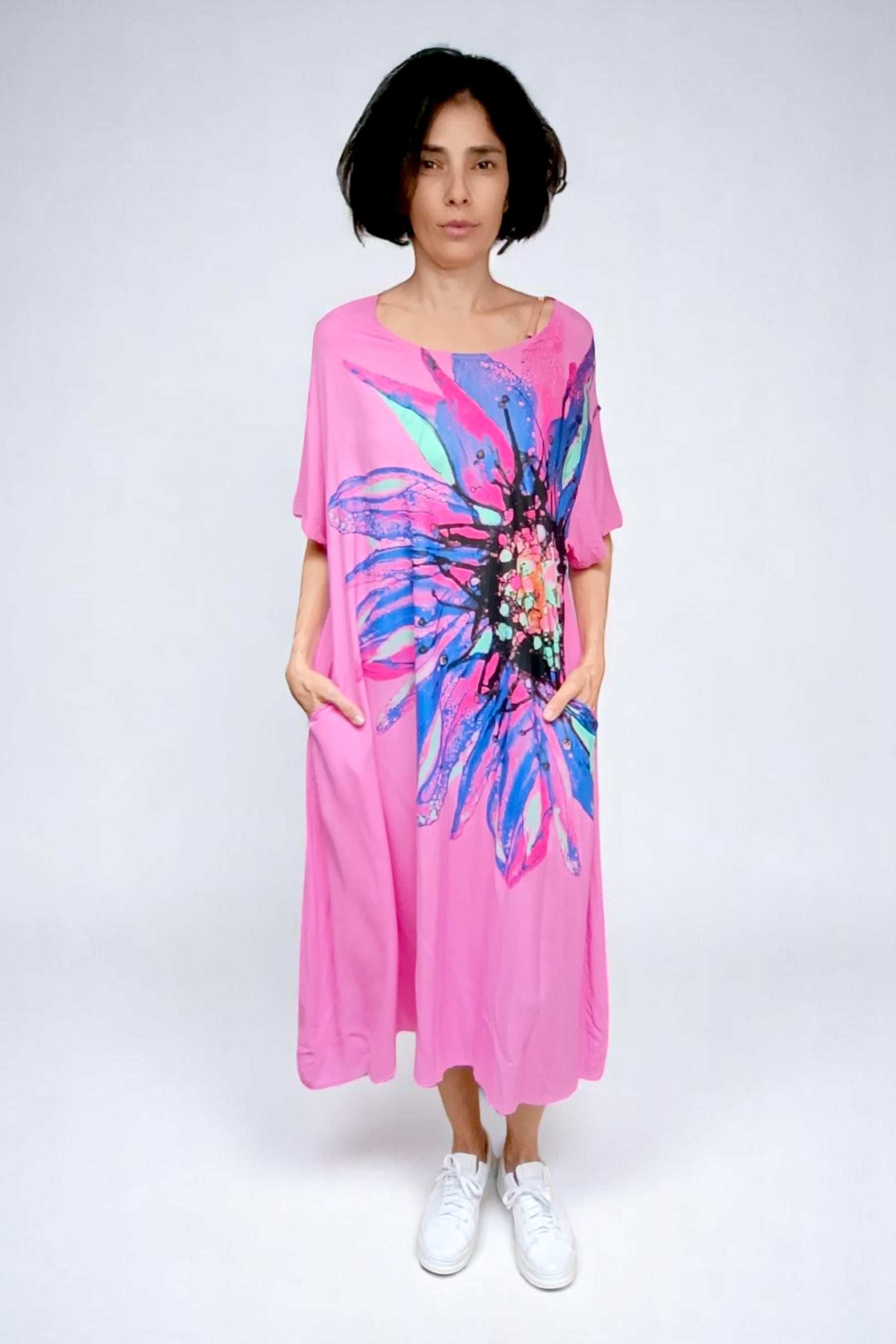 Model purtând rochia roz cu croi lejer, mâneci scurte și imprimeu floral vibrant