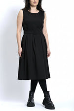 Rochie sarafan neagră cu pliuri, purtată cu bocanci, stil urban și echilibrat.