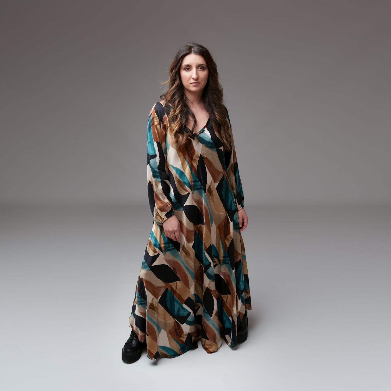 Rochie lungă din mătase cu imprimeu geometric în nuanțe pământii și turcoaz, purtată de model în studio.