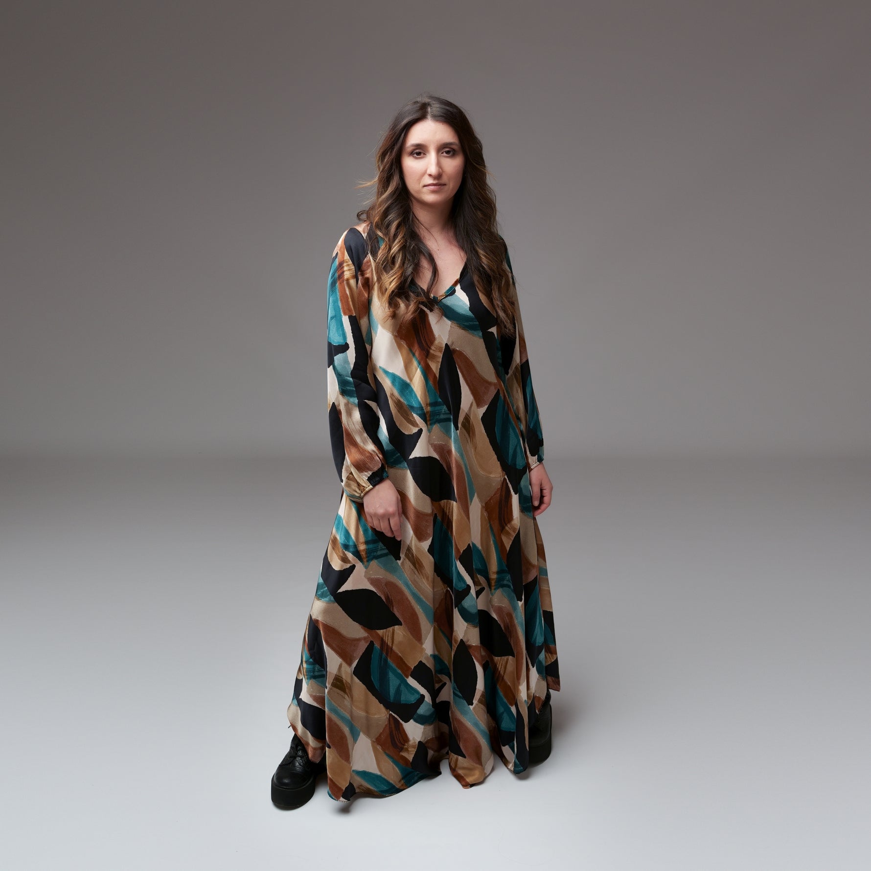 Rochie lungă din mătase cu imprimeu geometric în nuanțe pământii și turcoaz, purtată de model în studio.