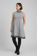 Rochie tricotată gri, fără mâneci, cu croială evazată și tiv decorativ în dungi contrast, purtată cu colanți negri.