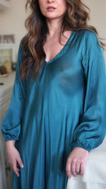 Rochie turcoaz satinată cu decolteu în V, purtată de model, fotografie de aproape cu accent pe material și croială.