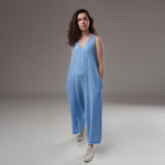 Salopetă culotte din in albastru, lejeră, cu decolteu în V, buzunare laterale și bretele reglabile, prezentată frontal pe model.
