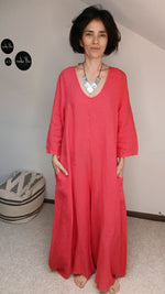 Salopetă portocaliu din in pe model, fundal interior, cu detalii decolteu și lungime generoasă.