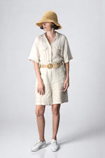 Salopetă scurtă crem din in, cu mâneci scurte, curea și buzunare frontale.