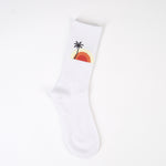 Șosetă albă tricotată, lungă până la gambă, cu motiv palmier și soare la apus.