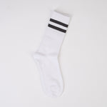 Șosetă lungă tricotată de culoare albă, cu două dungi negre în partea superioară, pe fundal alb