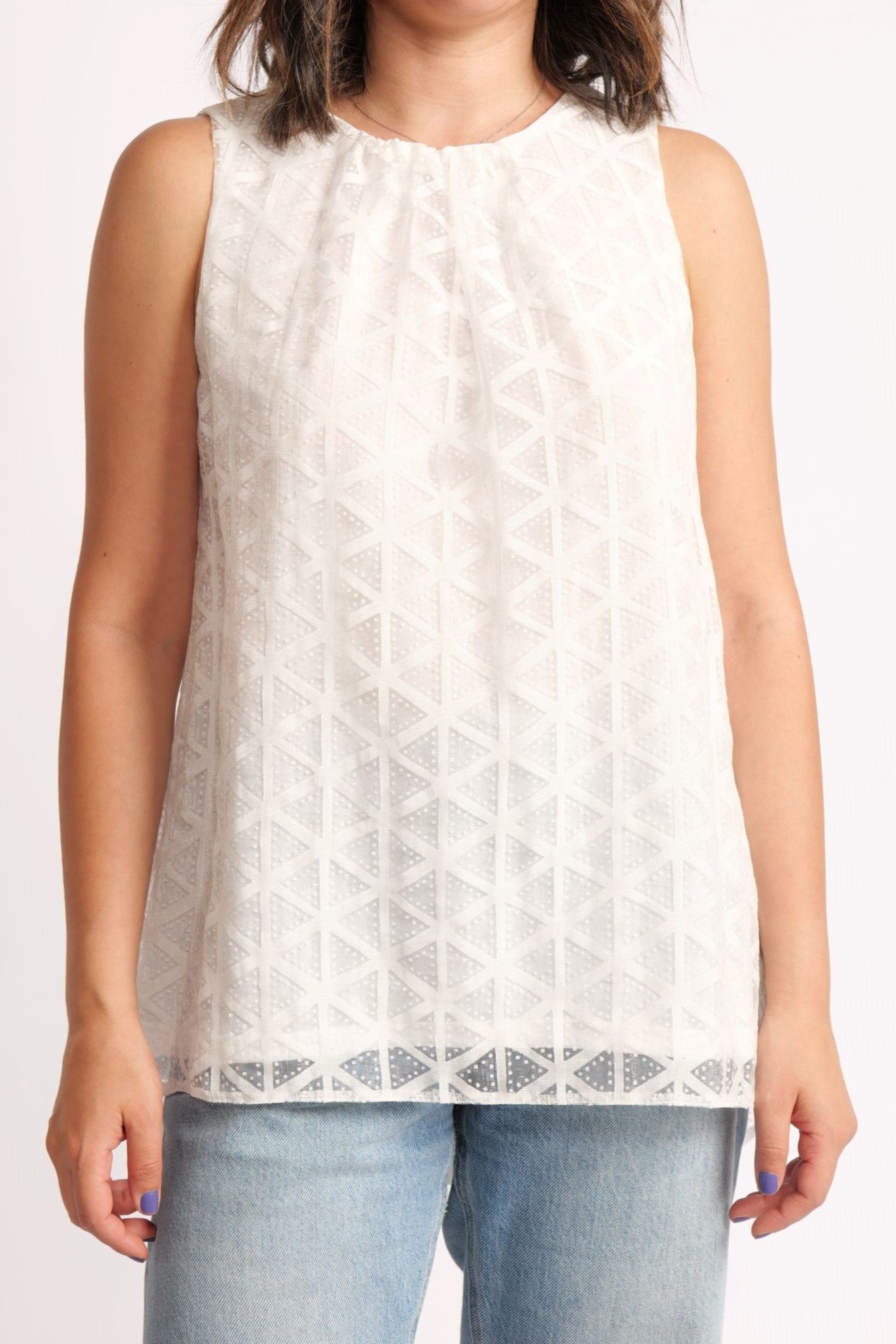 Detaliu apropiat al topului alb, cu dublură delicată și model geometric texturat.