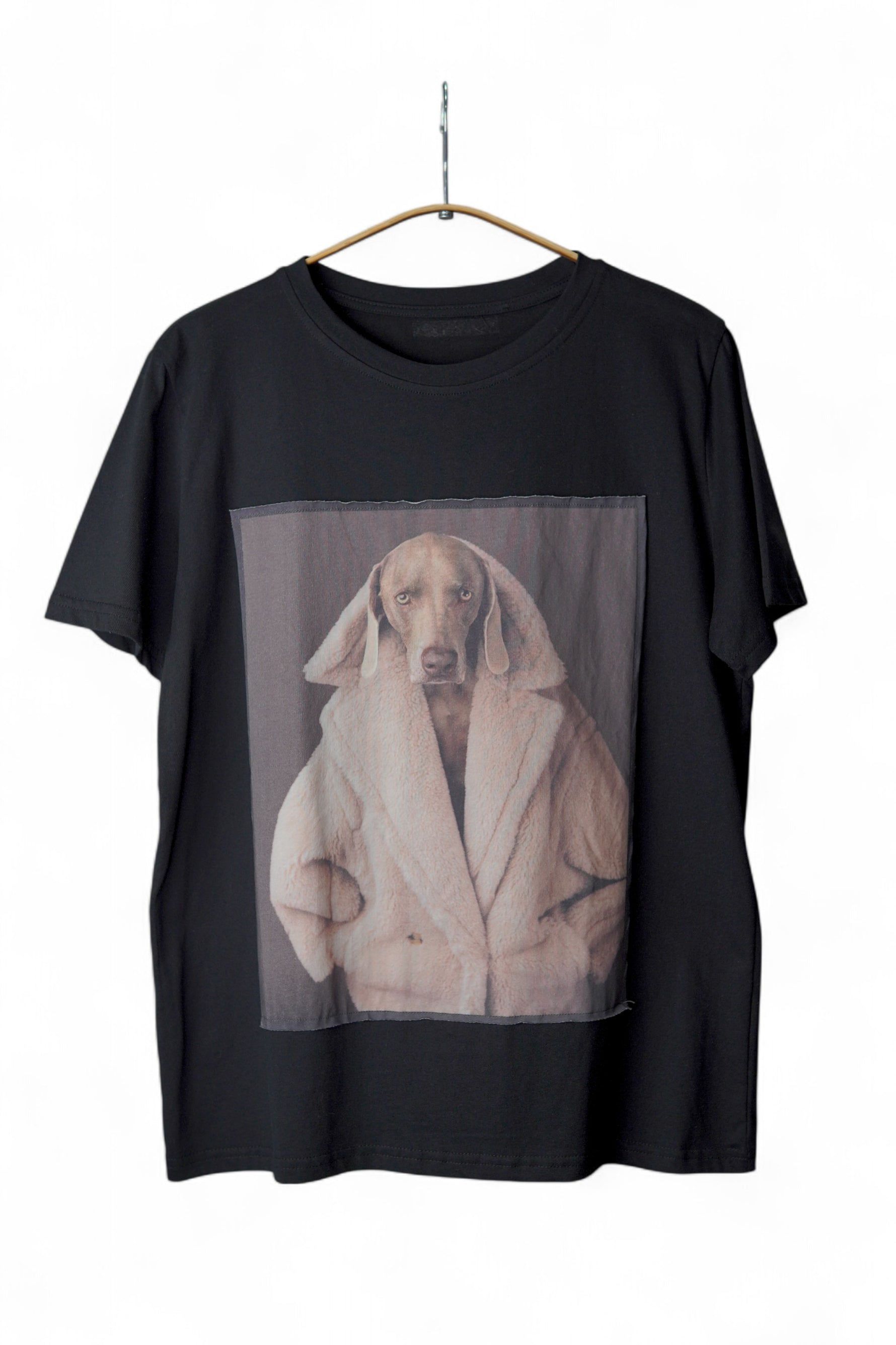 Tricou negru prezentat pe umeraș, cu imprimeu artistic al unui câine serios în haină pufoasă.