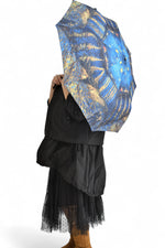 Umbrelă deschisă cu imprimeu inspirat din pictura „Noaptea Înstelată” a lui Vincent van Gogh, în nuanțe intense de albastru și galben.