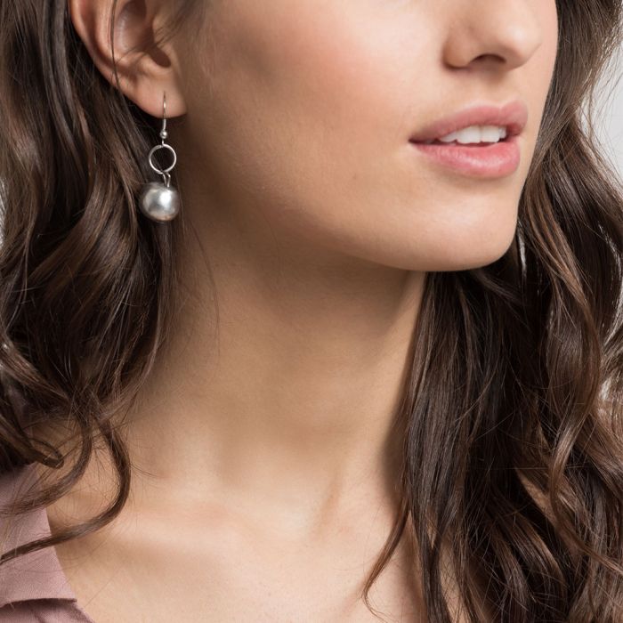 Cercei handmade din aluminiu reciclat, în formă de perlă argintie, purtați de o femeie – design minimalist și eco-friendly.