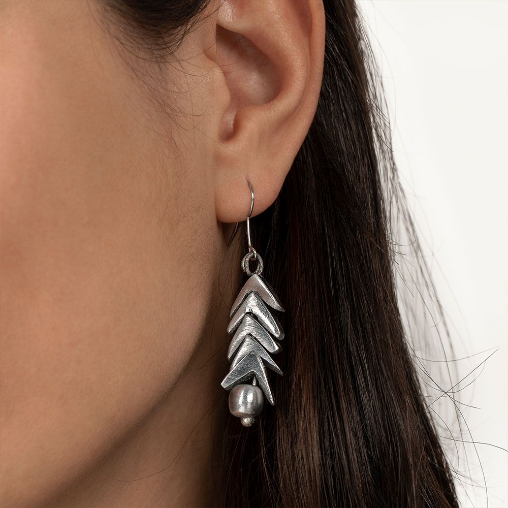 Cercei handmade din aluminiu reciclat, cu design în formă de săgeți și sferă, purtați de o femeie – bijuterie unică și eco-friendly.
