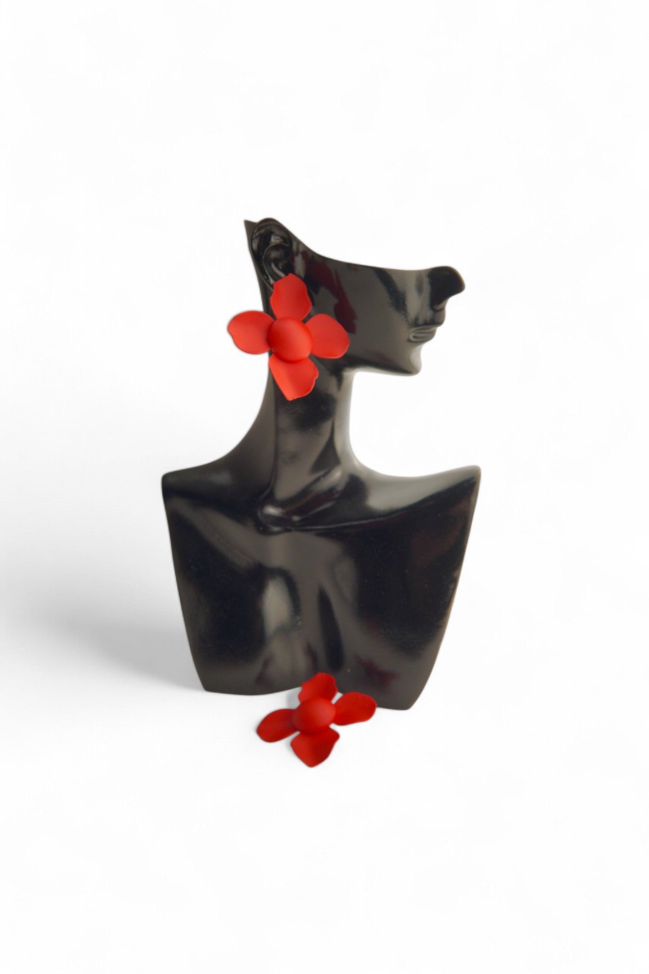 Cercei rosii purtați pe un bust elegant, accesoriu floral rafinat.