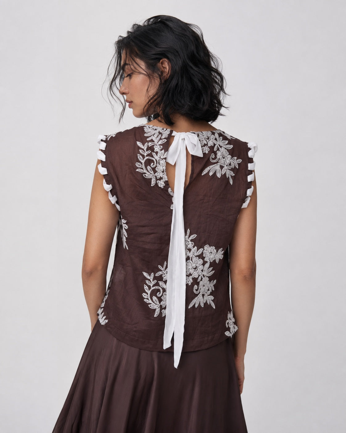 Top cu broderie florală și finisaje împletite, în nuanța maro, vedere din spate.