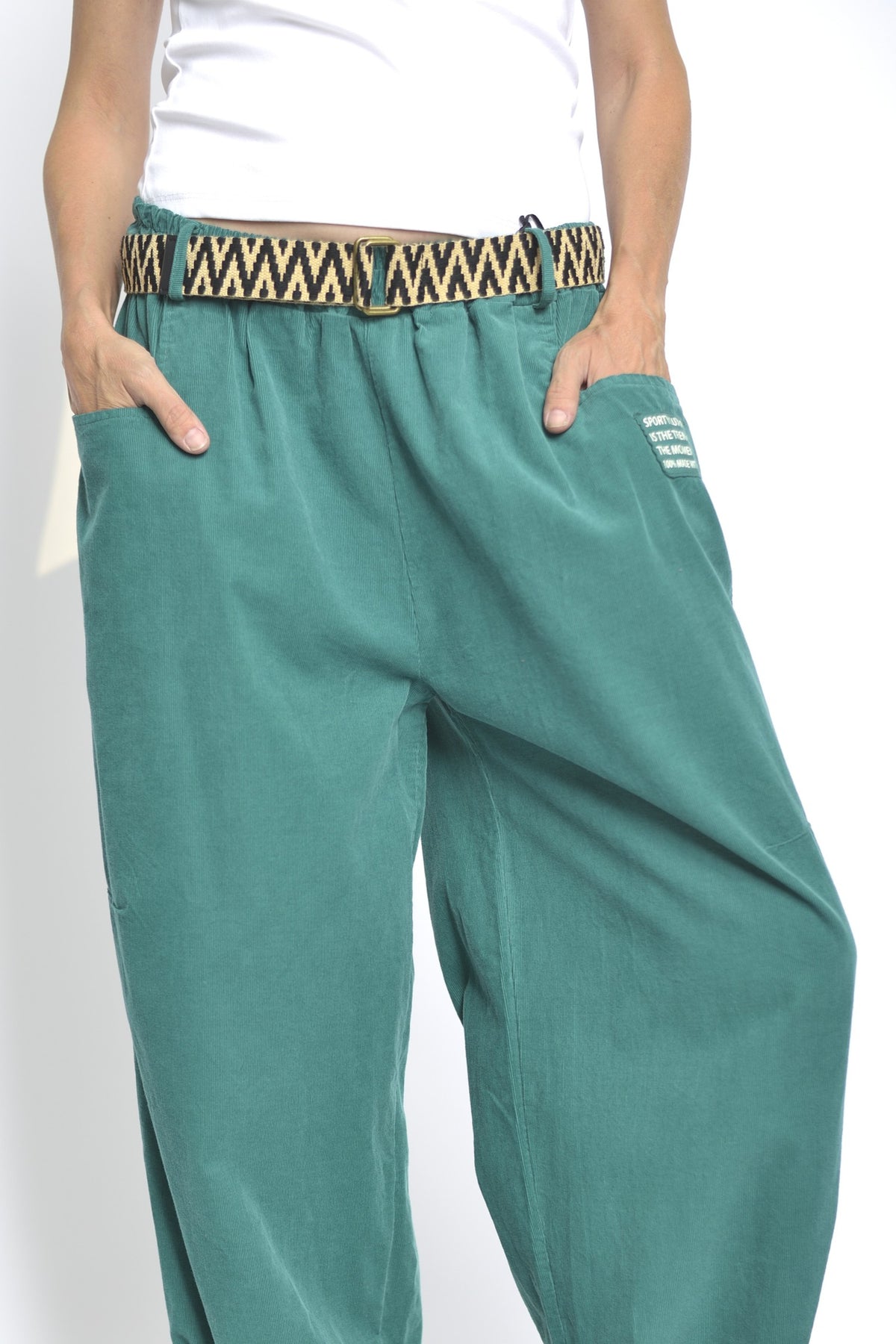 Pantaloni reiați lejeri cu talie elastică, în nuanța turcoaz închis, detaliu al taliei elastice și al curelei.