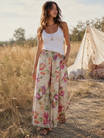 Pantaloni lungi evazați din in cu print floral roz-crem, purtați cu top alb, fundal boem câmp, All Above Boutique