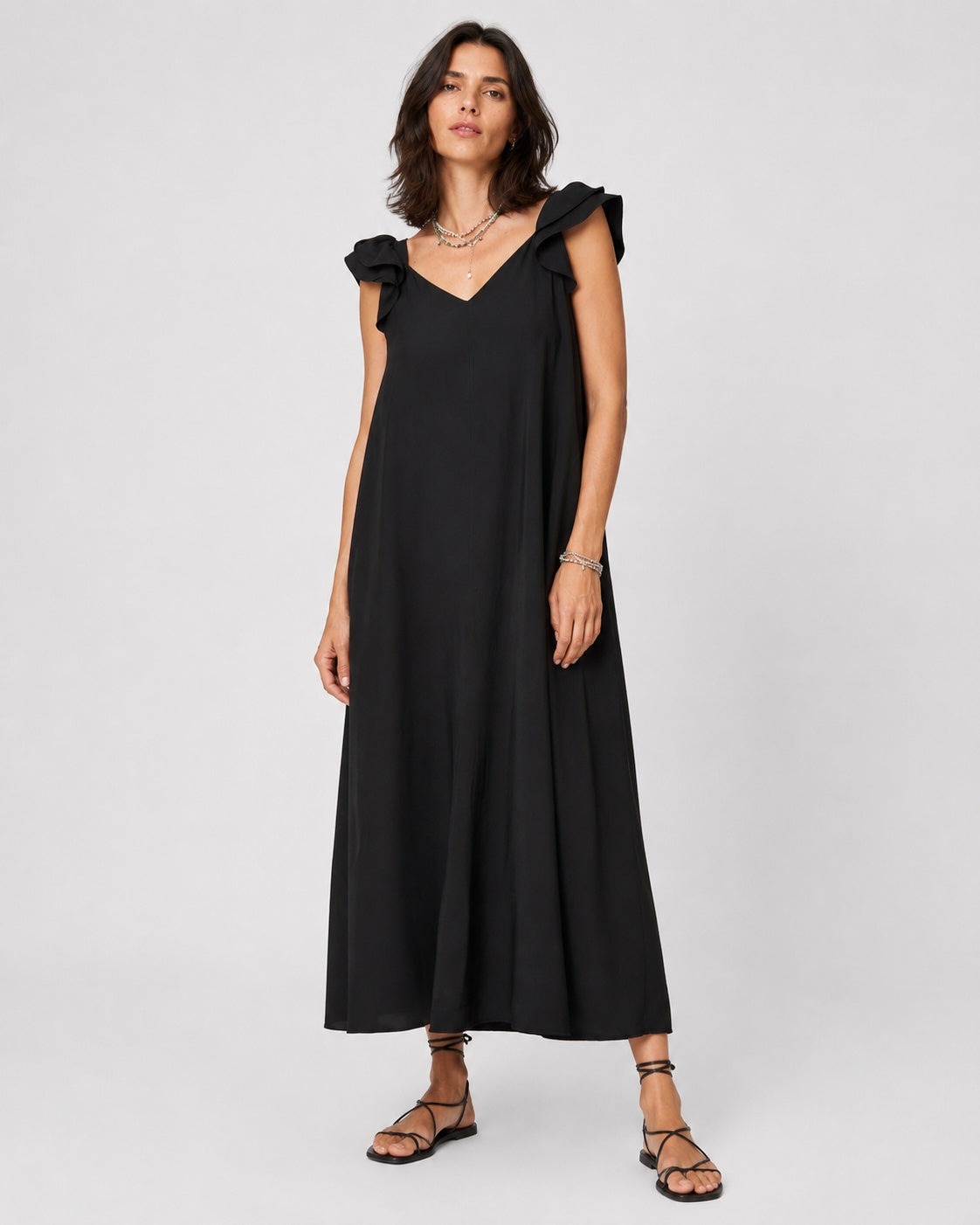 Rochie lungă din material catifelat cu volane la umeri și șnur la spate, în nuanța negru, vedere din față.