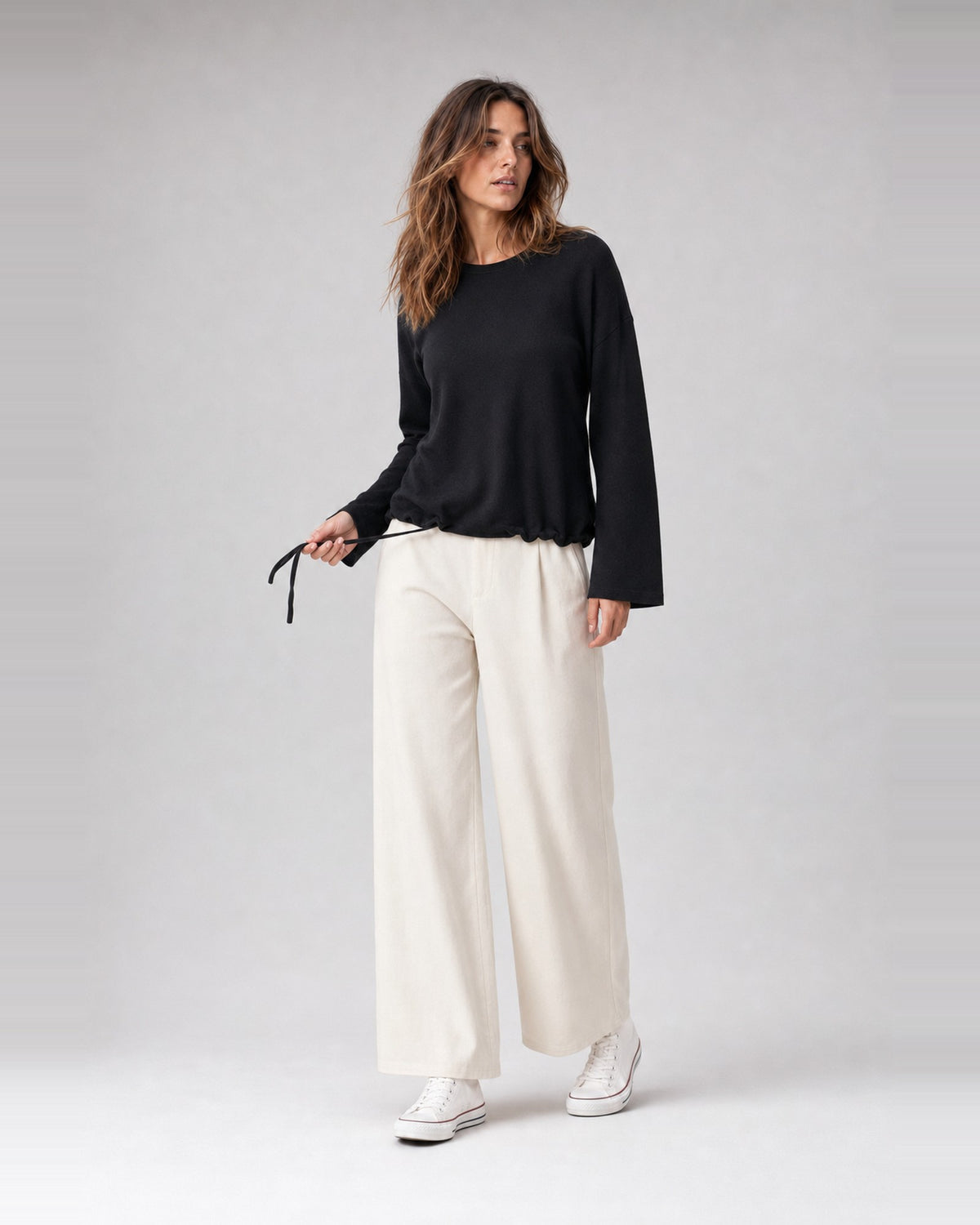 Bluză lejeră din tricot moale cu șnur la tiv, în nuanța neagră, purtată pe model, All Above Boutique