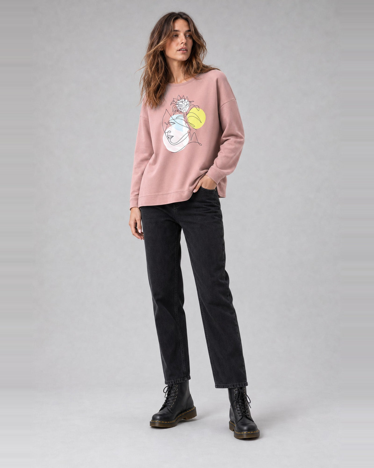 Bluză oversize din bumbac cu imprimeu chipuri, în nuanța roz deschis, purtată pe model, All Above Boutique