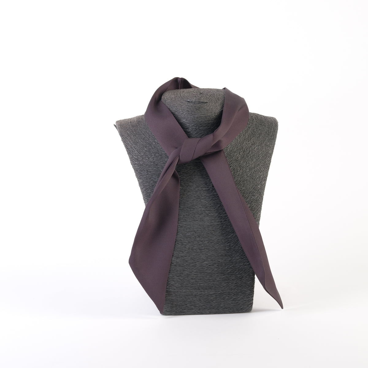 Eșarfă satinată expusă pe un suport gri, versatilă pentru a fi purtată ca bentiță, cravată sau accesoriu pentru geantă.