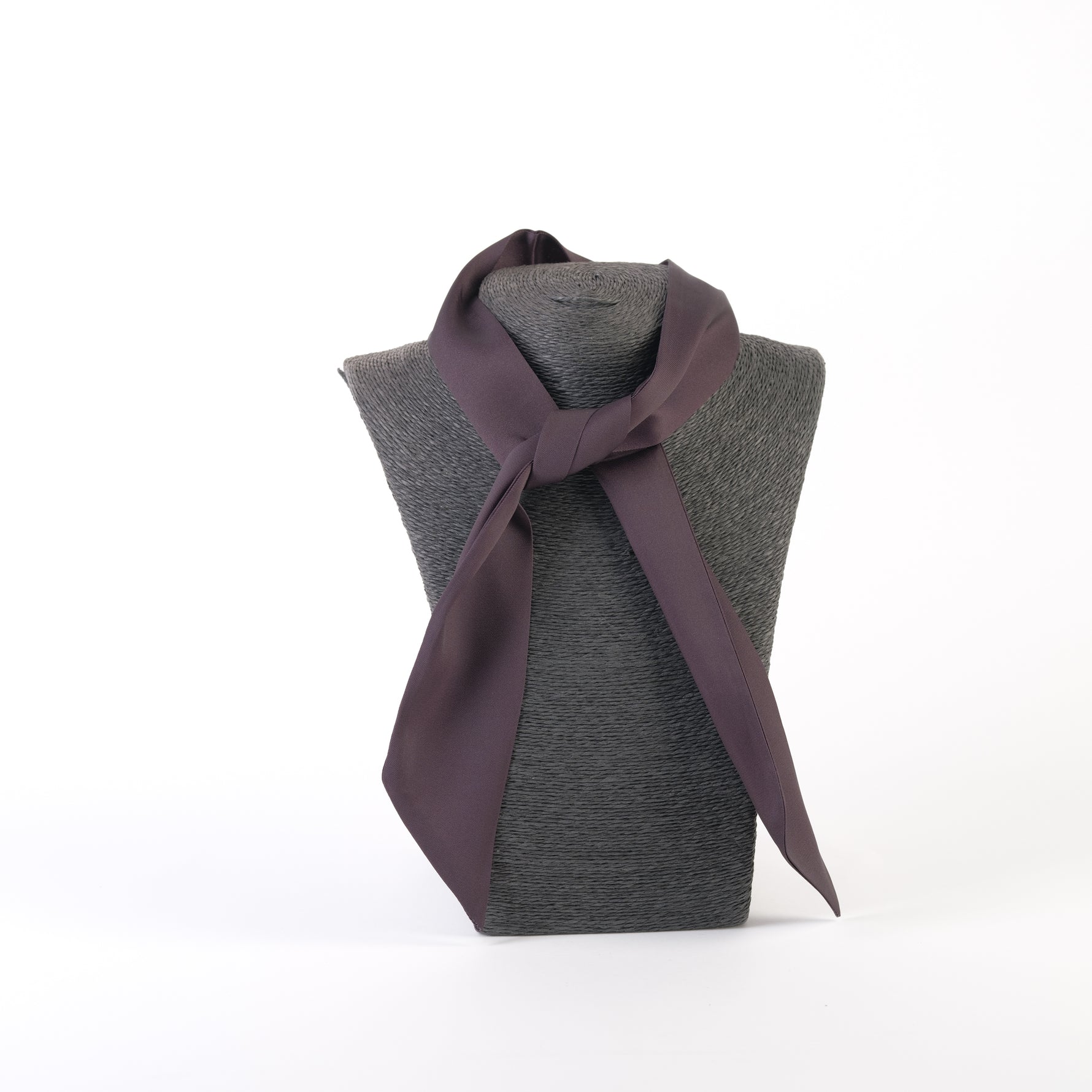Eșarfă satinată expusă pe un suport gri, versatilă pentru a fi purtată ca bentiță, cravată sau accesoriu pentru geantă.