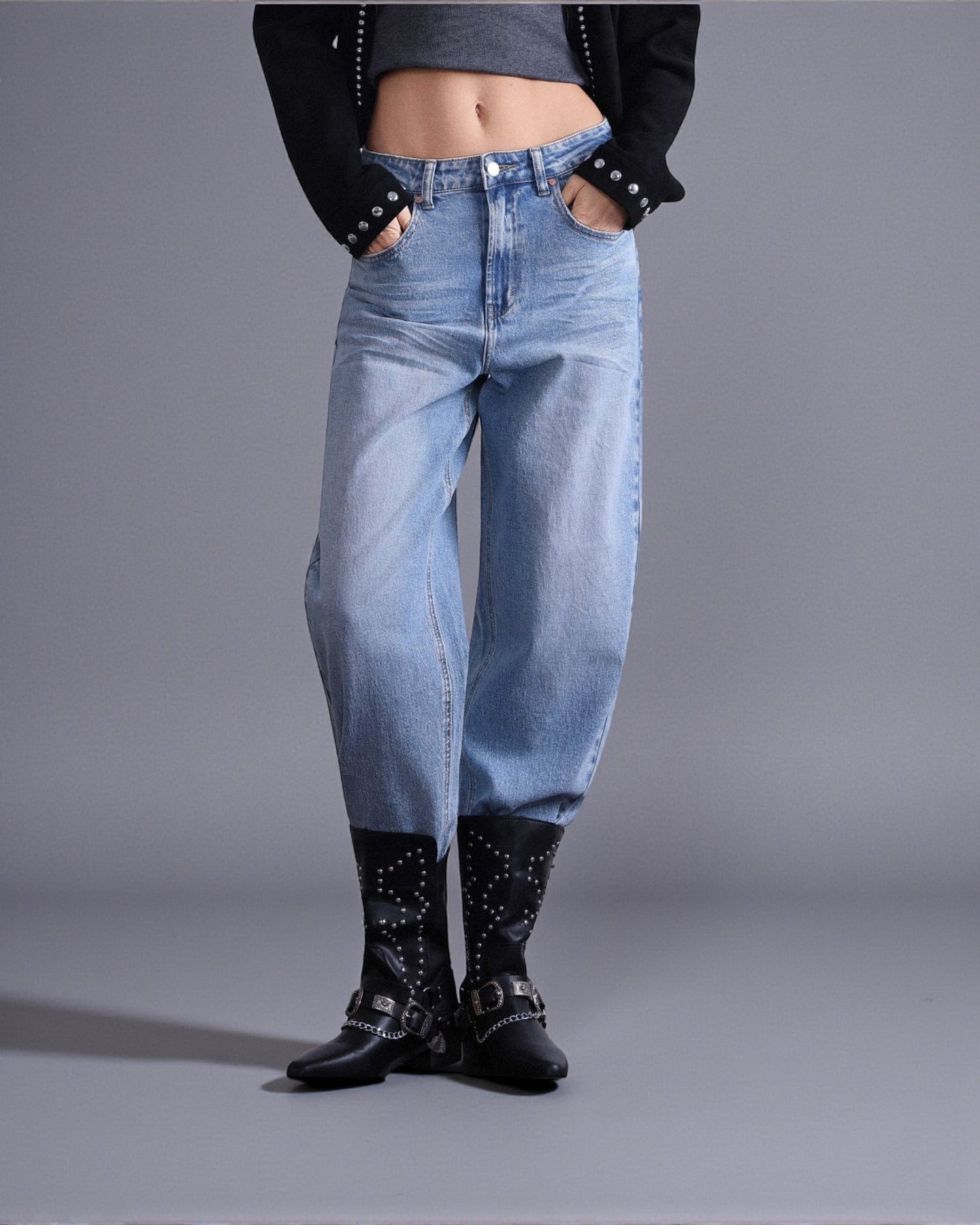 Model poartă blugi barrel fit din denim albastru, cu talie medie și croială lejeră, styling urban, vedere frontală.