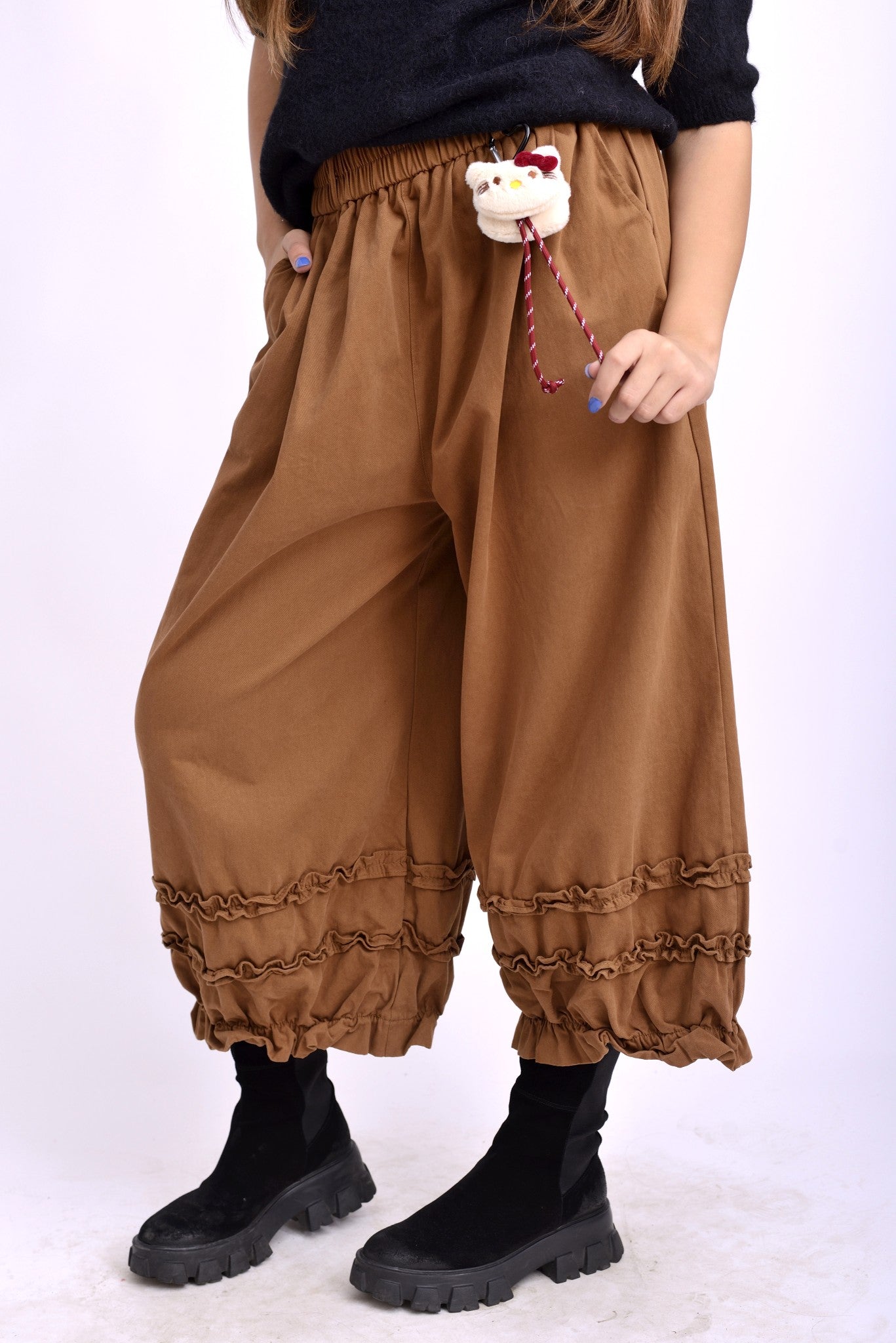 Vedere laterală a pantalonilor colorați cu talie elastică și tiv decorat cu volane.