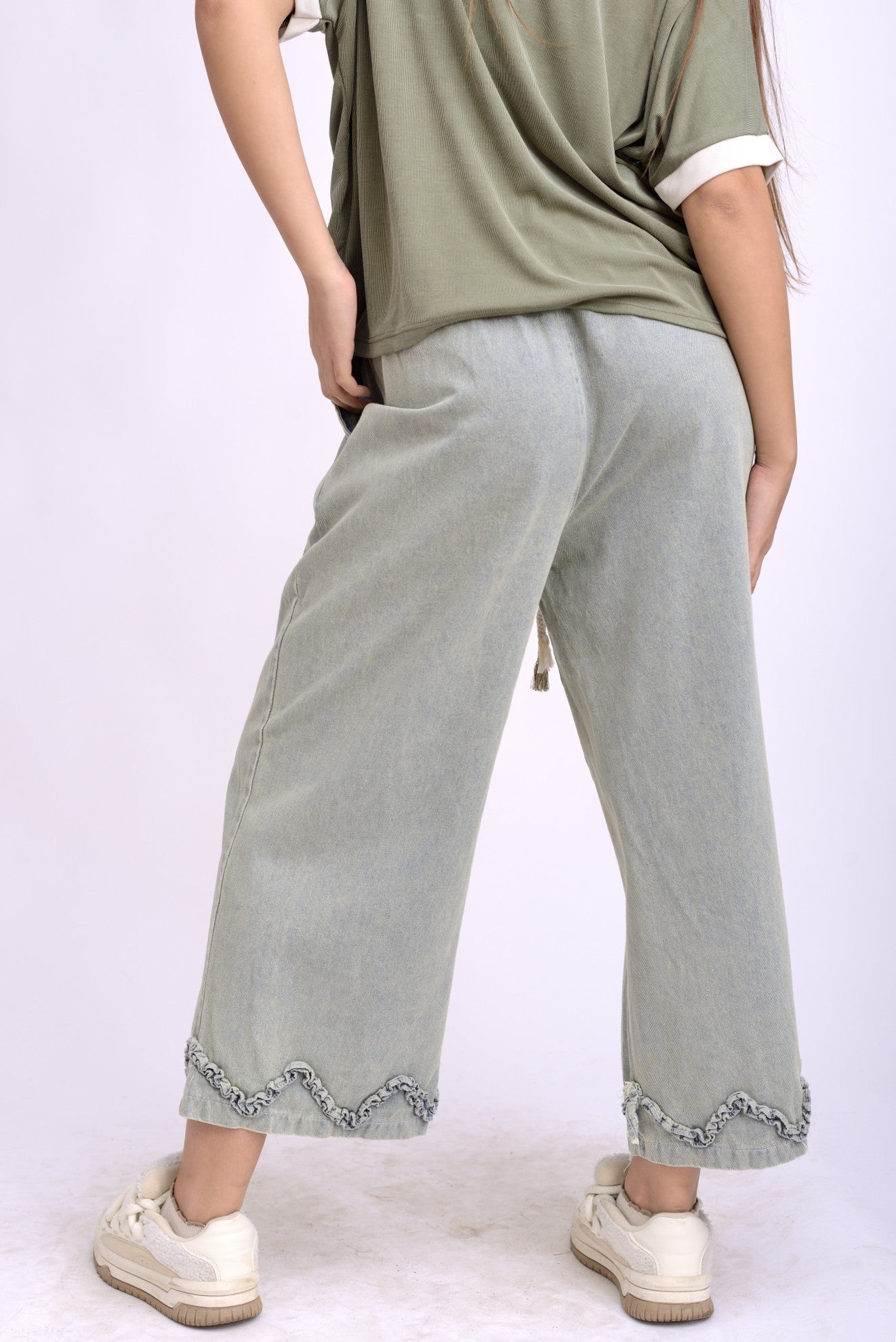 Blugi casual cu picior larg și volan la tiv, purtați cu un top verde kaki pentru un look urban chic.